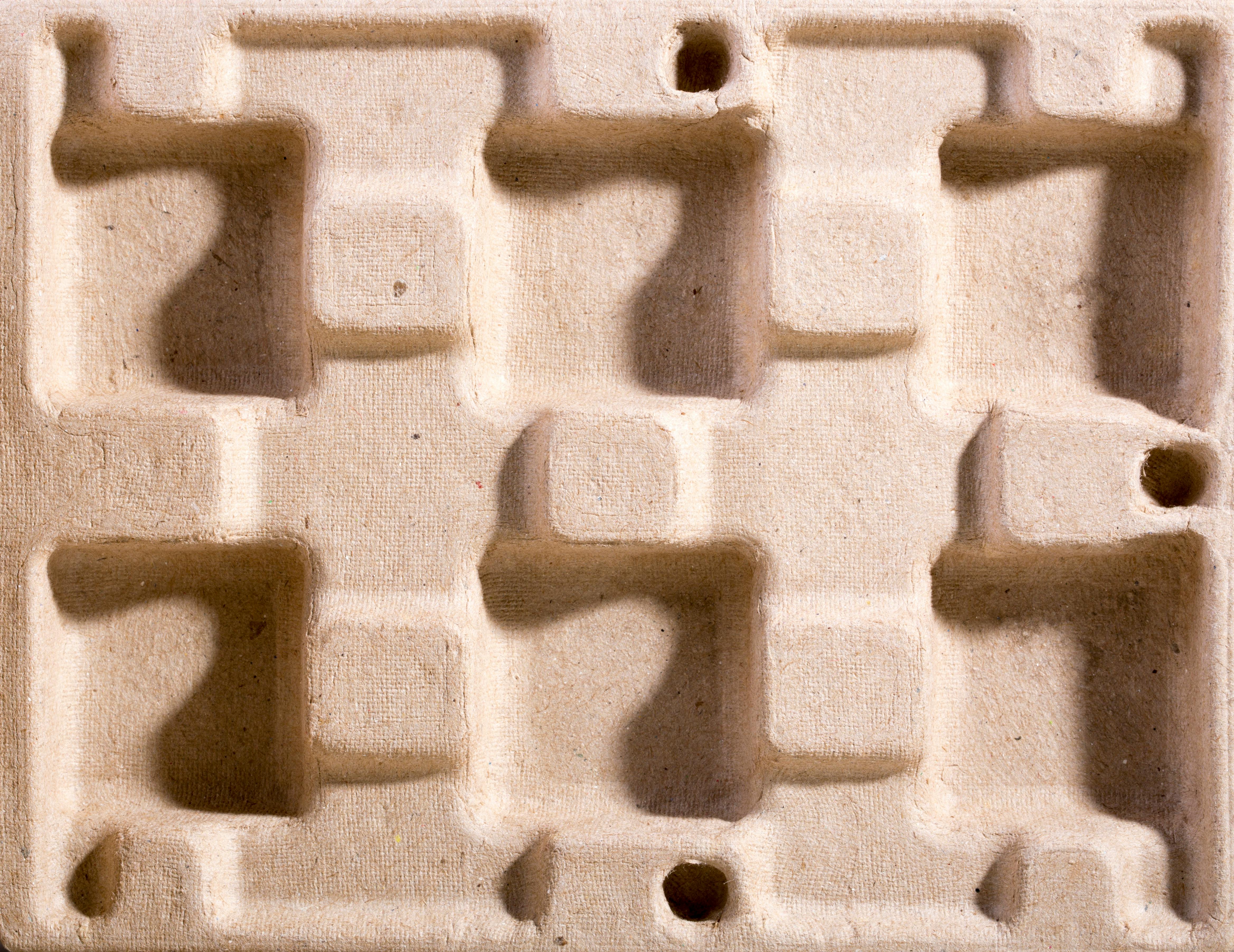 Close-up of an eco-friendly molded fiber packaging material with geometric indentations.